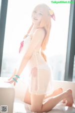 A woman in a white lingerie sitting on a bed.