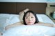 A woman laying on top of a bed with white sheets.