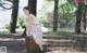 A woman sitting on top of a tree stump in a park.