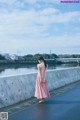 A woman in a pink dress standing on a bridge.