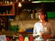 A woman standing in front of a counter in a kitchen.