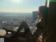 A woman sitting on a window sill looking out over a city.